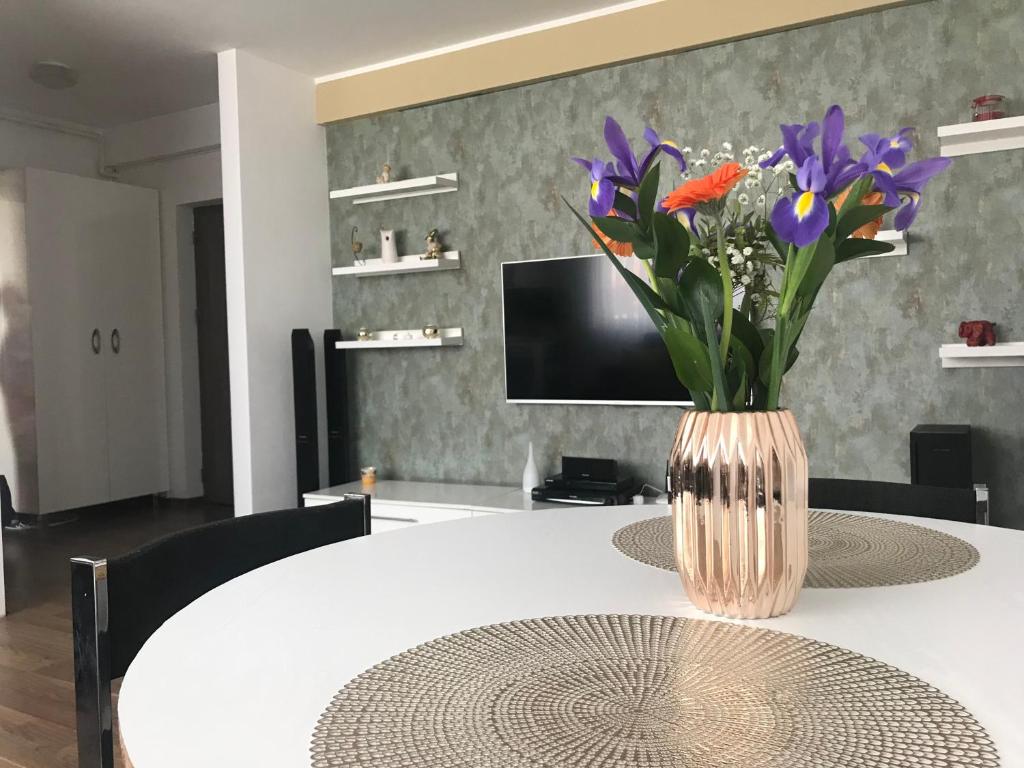 un vase de fleurs assis au-dessus d'une table dans l'établissement Pipera Lake View Bright Apartament, à Bucarest