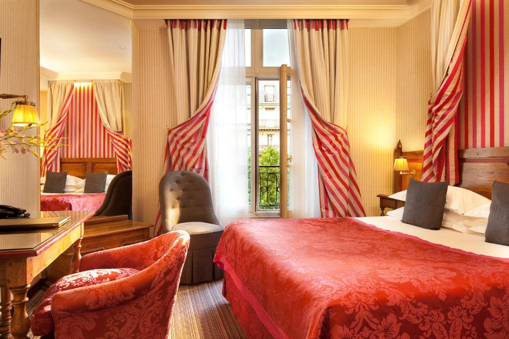 パリにあるオ マノワール サン ジェルマンのベッド2台とデスクが備わるホテルルームです。