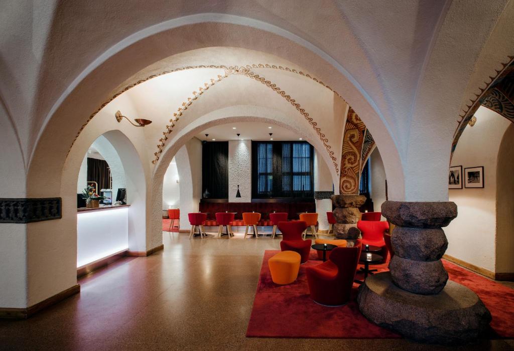 a lobby with arches and red chairs and a table at GLO Hotel Art in Helsinki