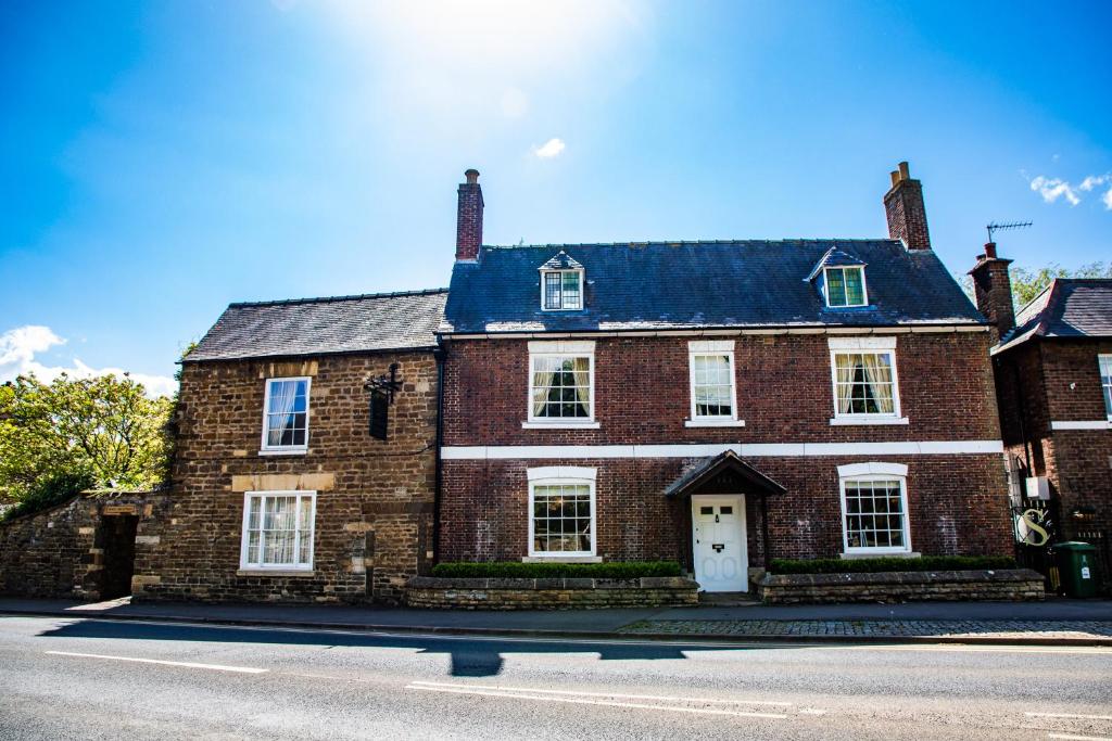 um grande edifício de tijolos vermelhos com uma porta branca em Wisteria Hotel em Oakham