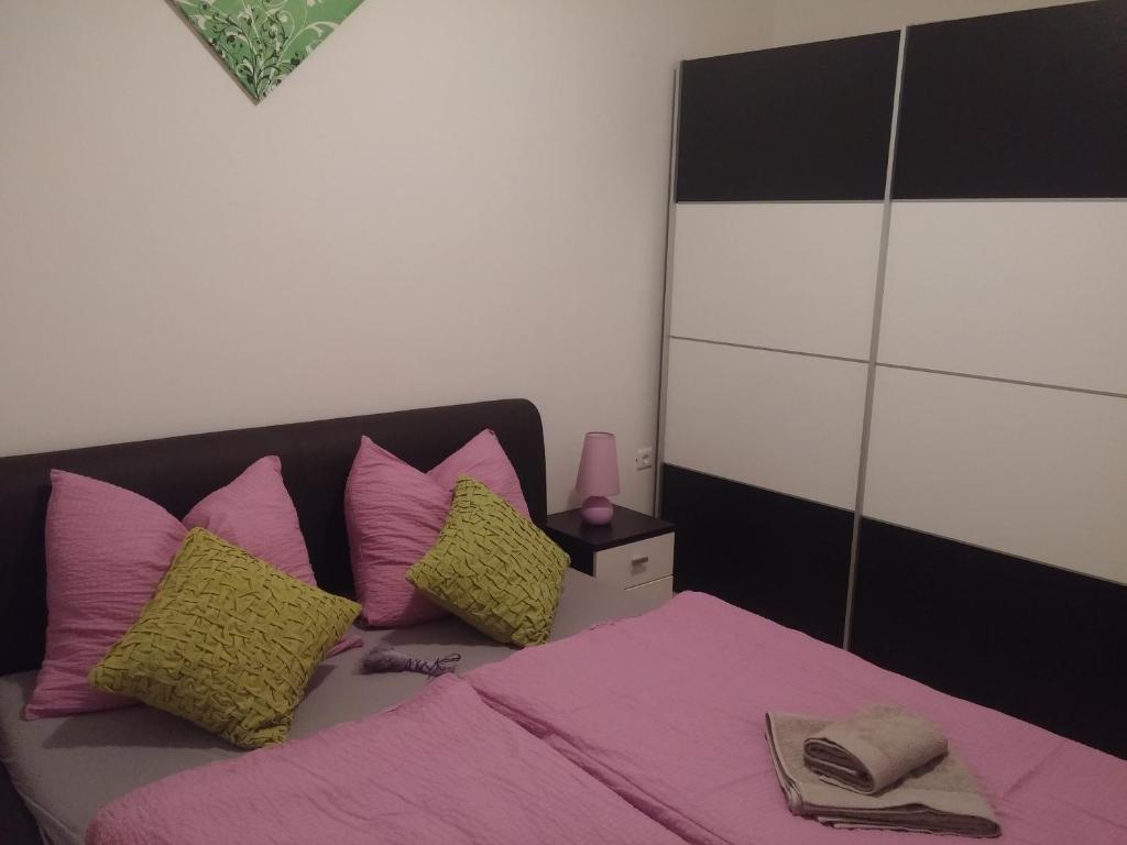 una camera da letto con un letto con cuscini rosa e gialli di Hostel **Casa del Sole** a Klenovica