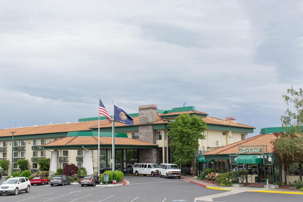 a hotel with cars parked in front of a parking lot at Rogue Regency Inn & Suites in Medford