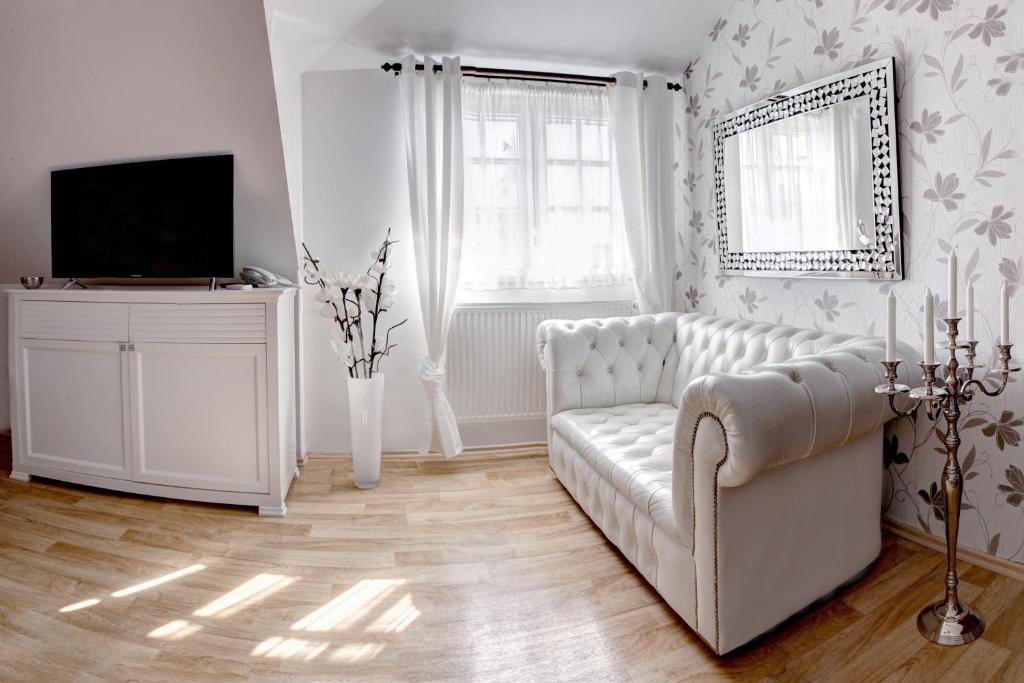 sala de estar con sofá blanco y TV en Penzion Tillerova vila, en Lázně Bohdaneč