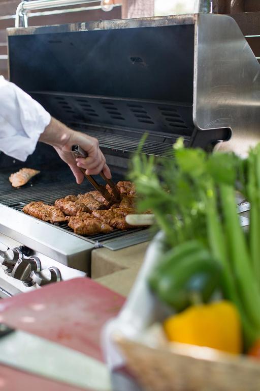 a person is cooking food on a grill at Rogue Regency Inn & Suites in Medford
