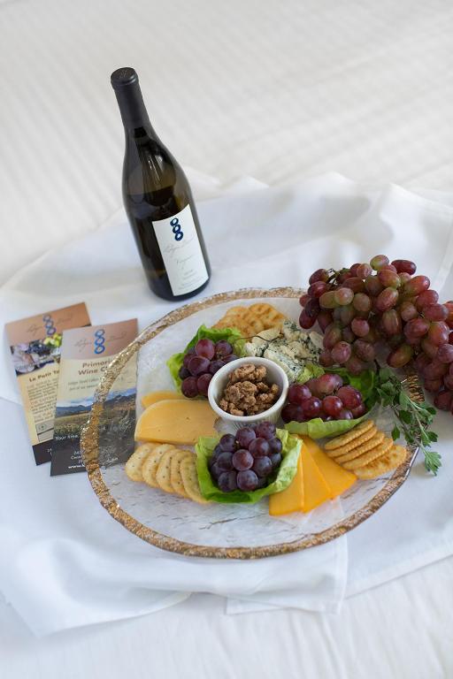 a plate of food with grapes and cheese and a bottle of wine at Rogue Regency Inn & Suites in Medford