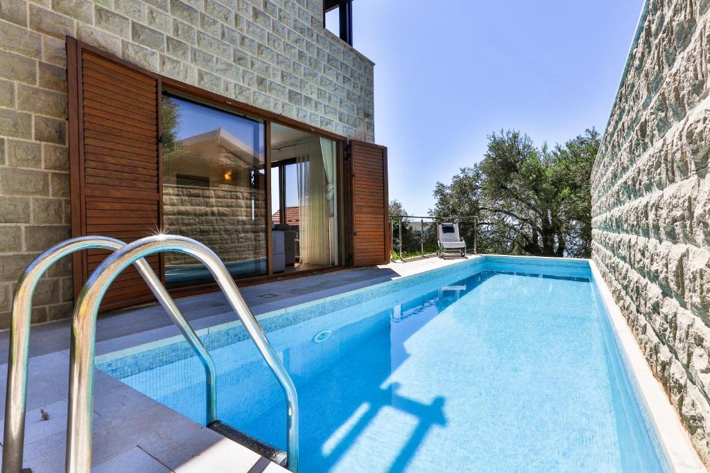 a swimming pool in front of a house at Villa Rijeka Rezevici in Petrovac na Moru