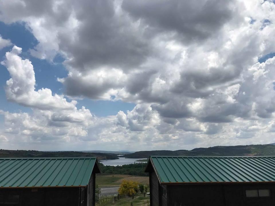 a view of a lake and a barn under a cloudy sky at Monte do Azibo Glamping in Podence