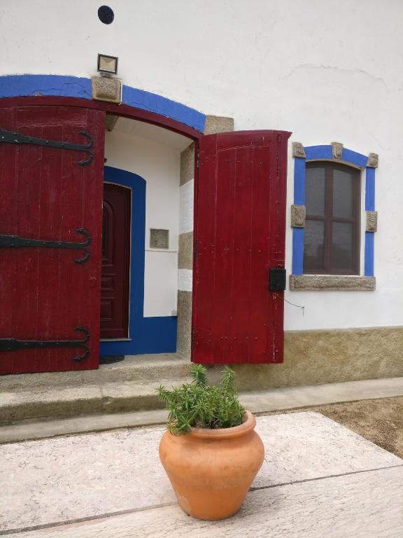 a pot sitting in front of a building with red and blue doors at Quinta da Abrunheira - Gustavo Eiffel in Ciborro