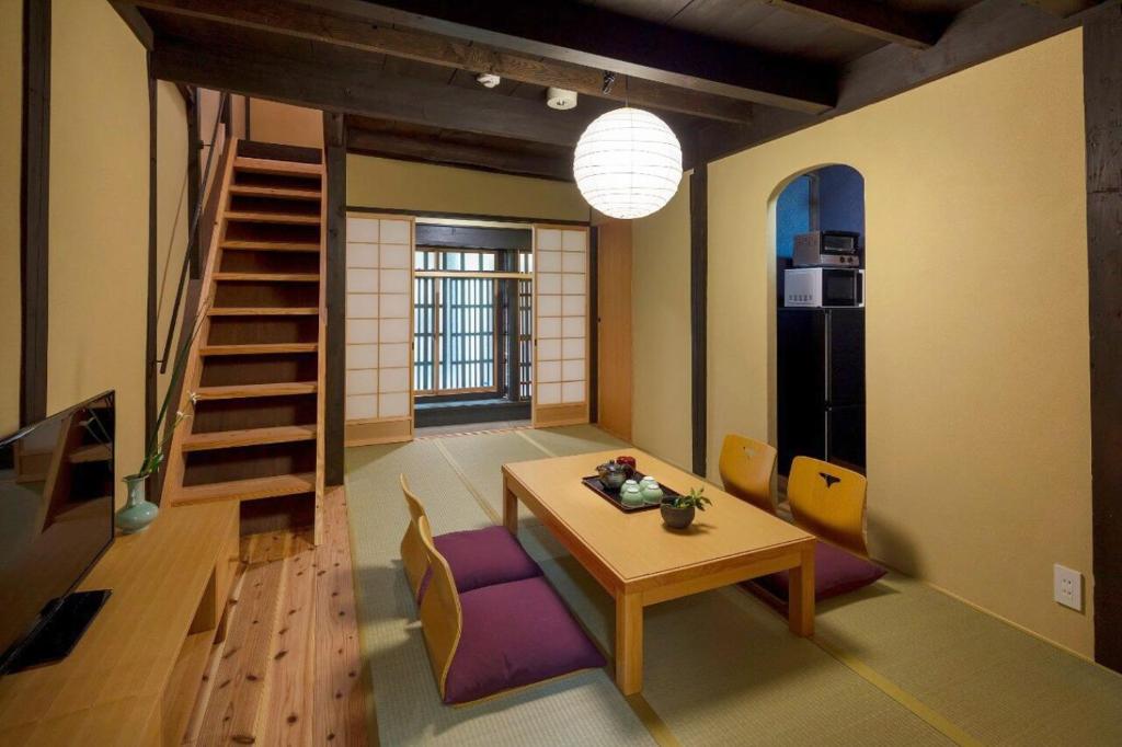 a room with a table and chairs and a staircase at Kumashu an Machiya House in Kyoto