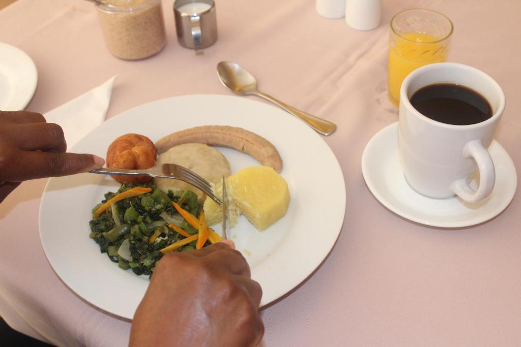a person eating a plate of food with a cup of coffee at Altamont West Hotel in Montego Bay