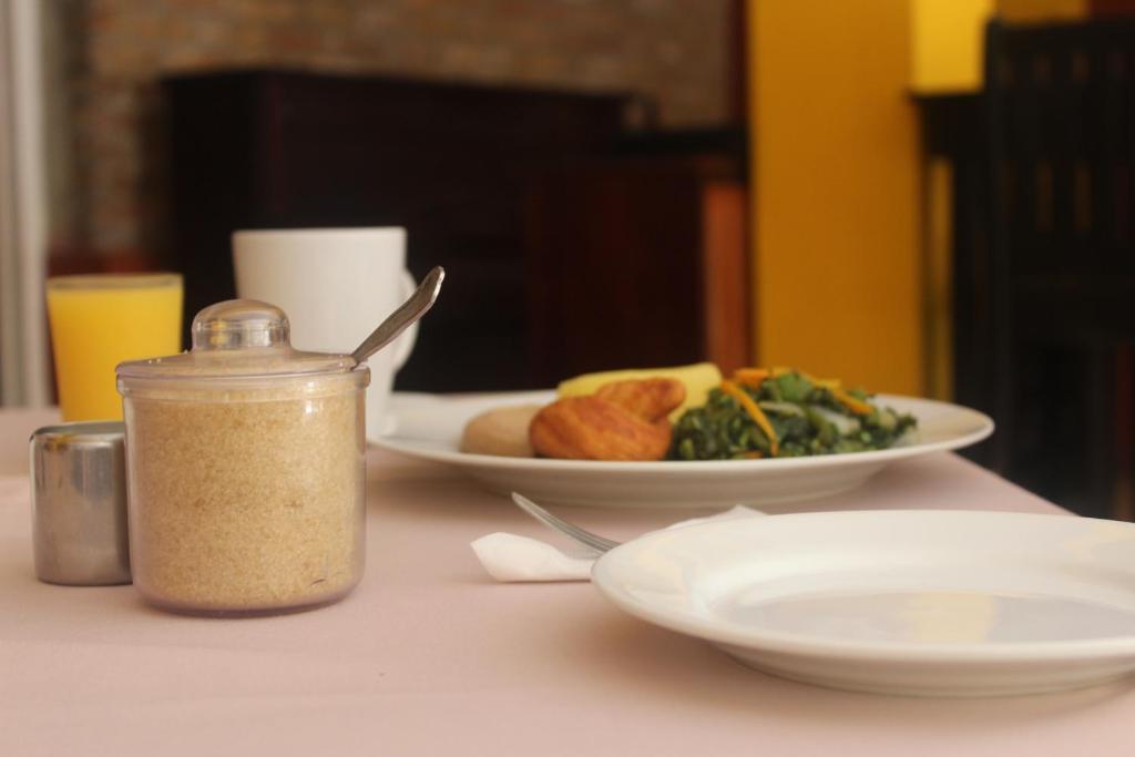 a table with a plate of food and a jar of seasoning at Altamont West Hotel in Montego Bay