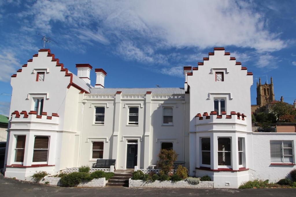 une maison blanche avec deux flèches en haut dans l'établissement Trinity Hill Apartments, à Hobart