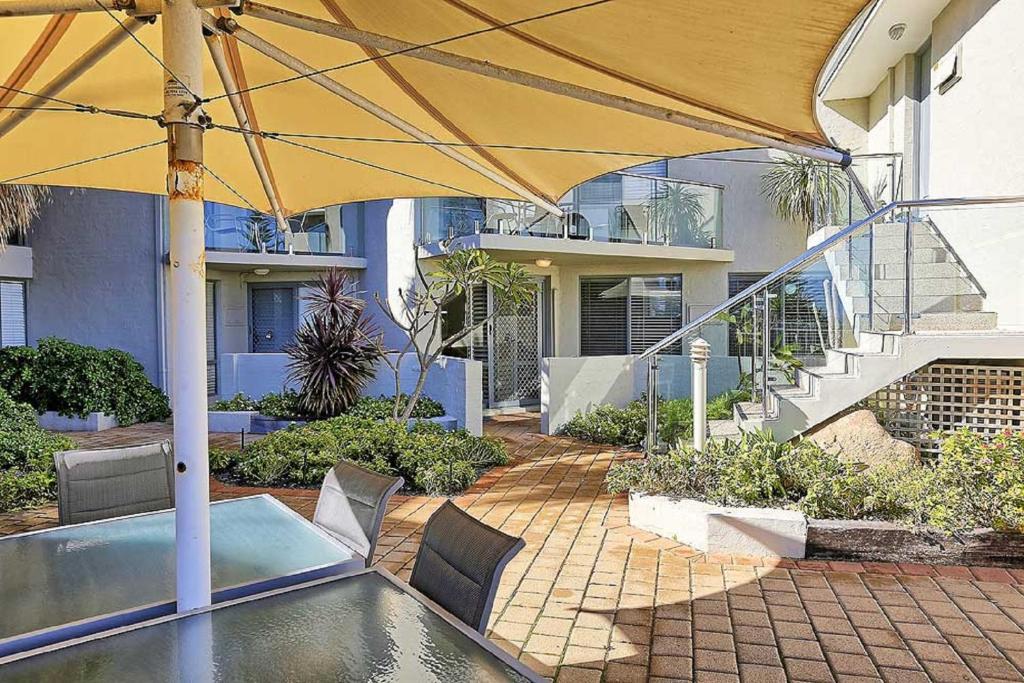 a patio with an umbrella and a swimming pool at Beachfront @ Scarbs in Perth