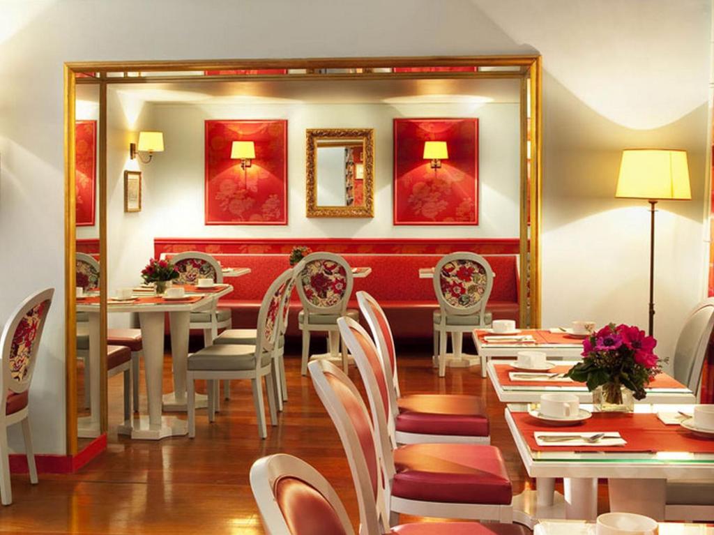 a dining room with tables and chairs and a mirror at Hotel Louvre Bons Enfants in Paris