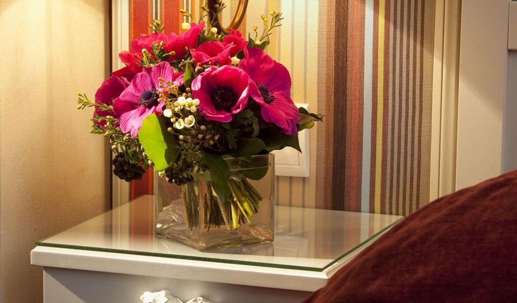 a vase filled with pink flowers on a glass table at Hotel Louvre Bons Enfants in Paris