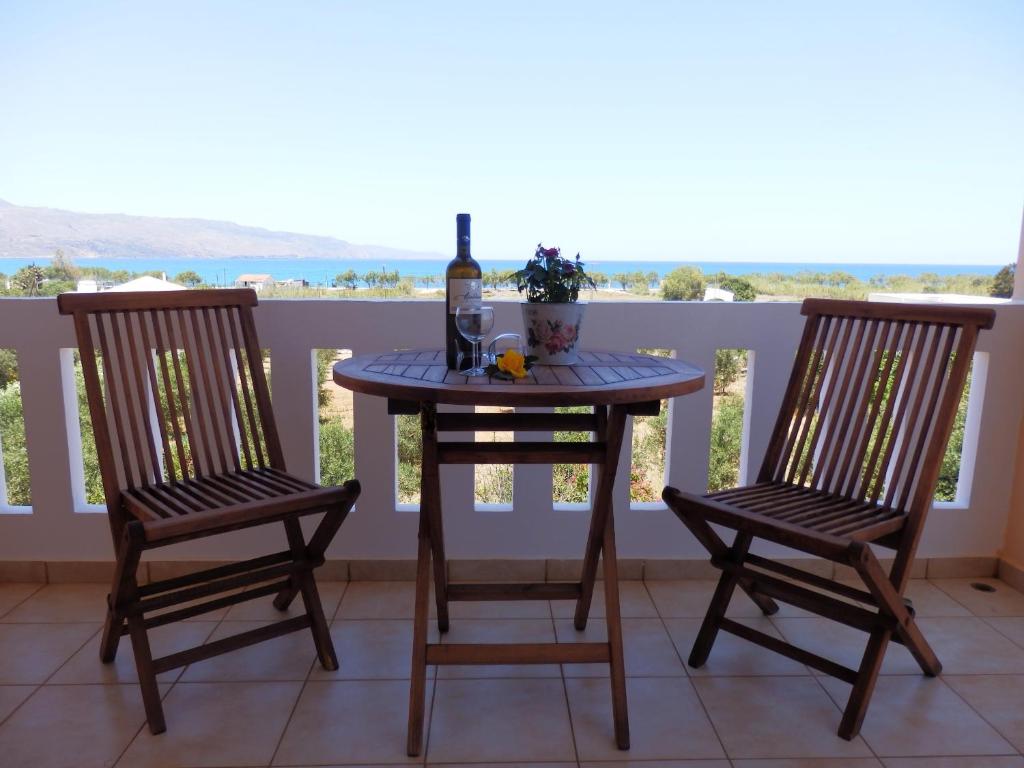 uma mesa com uma garrafa de vinho e duas cadeiras em Maro Suites em Tavronítis