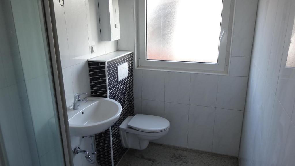a bathroom with a toilet and a sink and a window at Huus Veertein in Neuharlingersiel