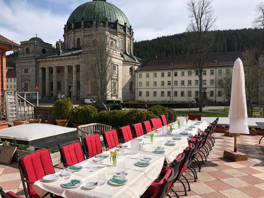 une longue table avec des chaises rouges et un bâtiment dans l'établissement Klostermeisterhaus, à St. Blasien