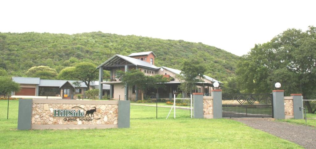 a building with a sign in front of a field at Arotin Game Lodge in Brits
