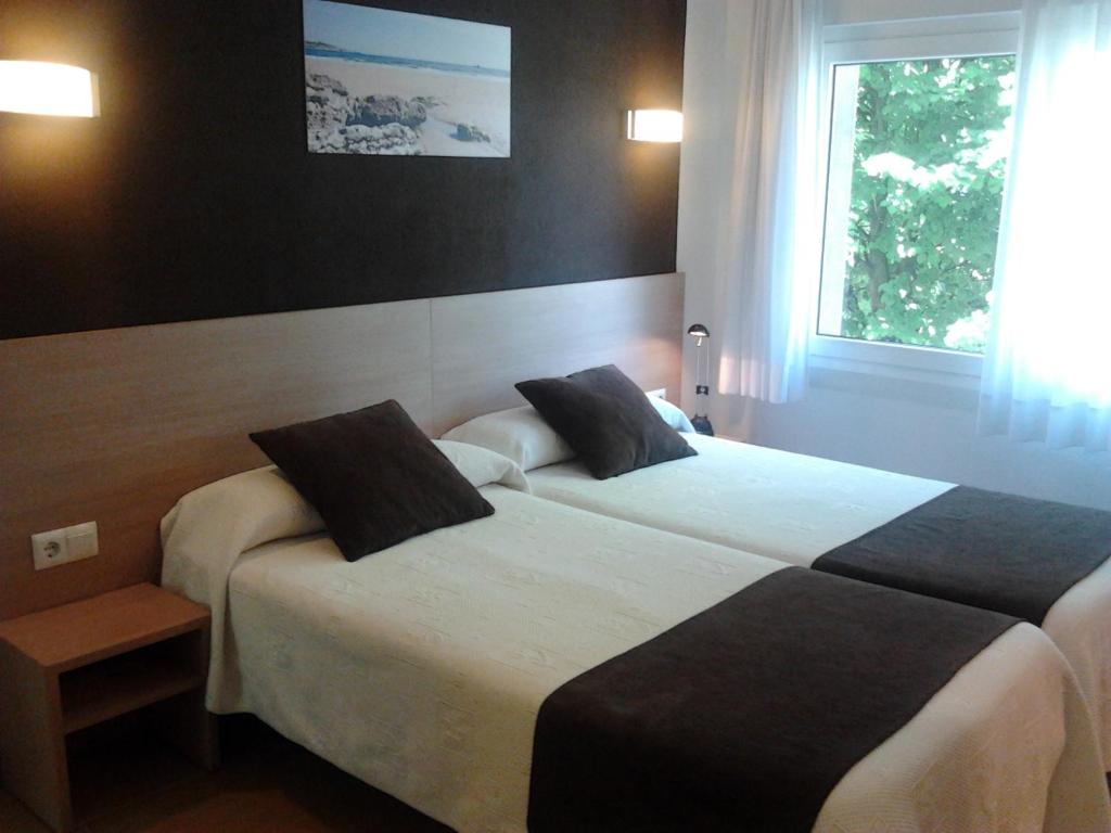 Habitación de hotel con 2 camas y ventana en Hostal Rocamar, en Santander