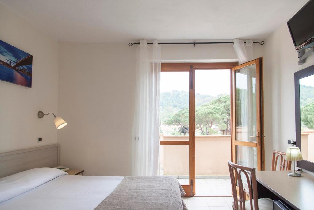 um quarto com uma cama, uma secretária e uma janela em Residence Hotel Villa Mare em Portoferraio