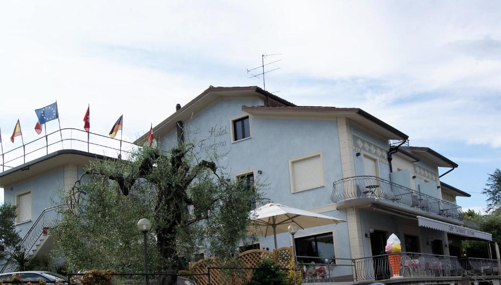 Un bâtiment blanc avec des drapeaux au-dessus dans l'établissement Hotel Francesco, à Padenghe sul Garda