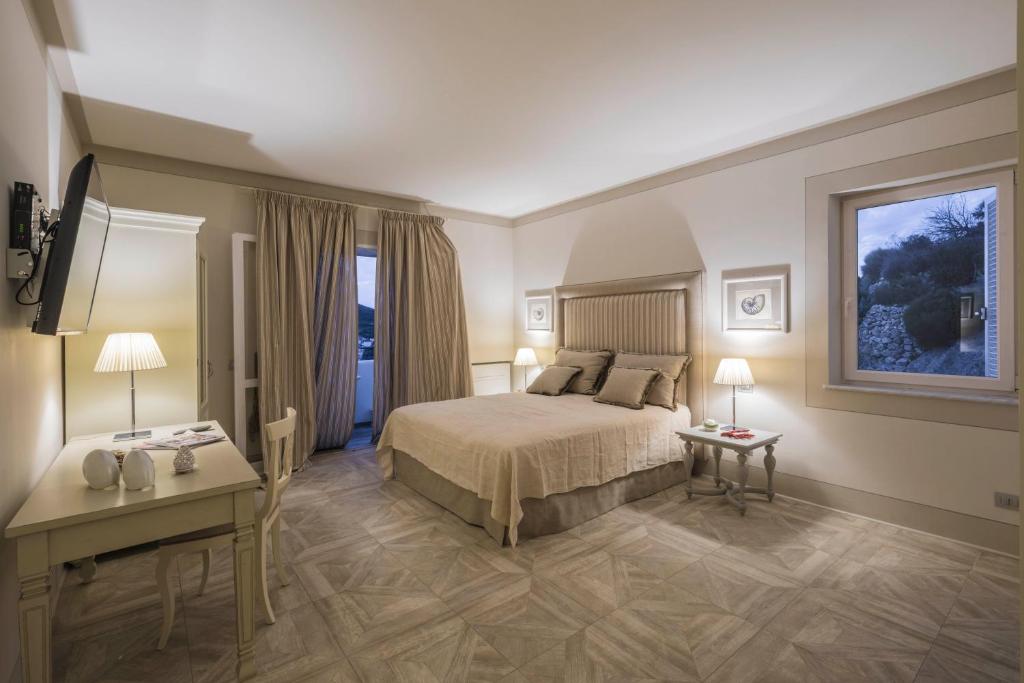 ein Hotelzimmer mit einem Bett und einem Schreibtisch in der Unterkunft Maridea Casa Vacanza- Le Alcove sul Mare Suites in Ponza