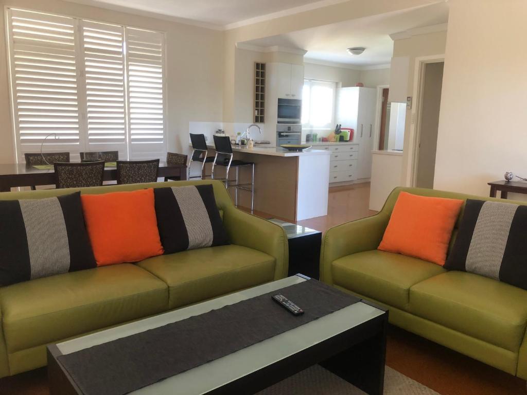 a living room with two green couches and a kitchen at Allora Apartment Applecross in Perth