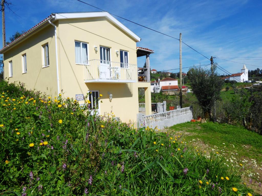 ein kleines gelbes Haus auf einem Hügel mit Blumen in der Unterkunft Casa da Casimira in Miranda do Corvo