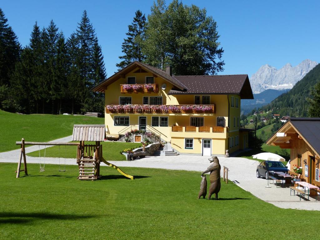 a large yellow house with a bear statue in the yard at Schieplechnerhof in Schladming