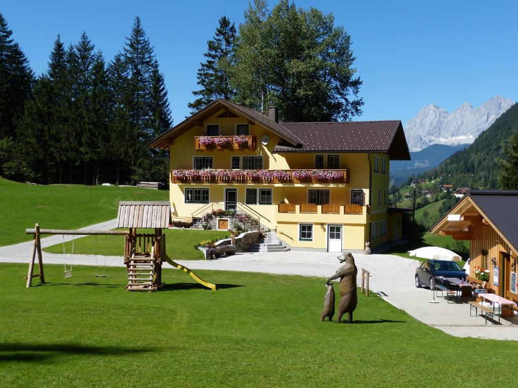 een groot geel huis met een standbeeld van een beer in de tuin bij Schieplechnerhof in Schladming