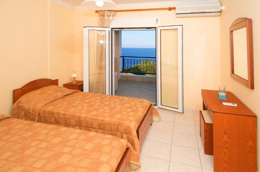 a hotel room with two beds and a balcony at Mari-Christi Apartments in Póros Kefalonias