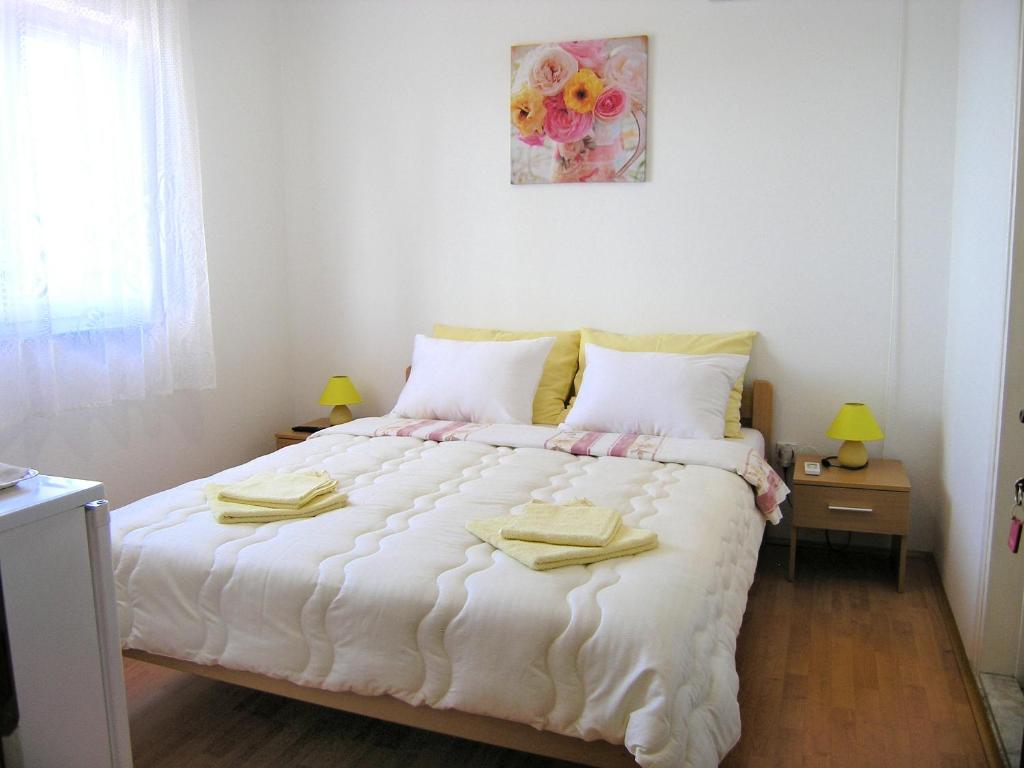 a bedroom with a white bed with two towels on it at Rooms Valentino in Vrh