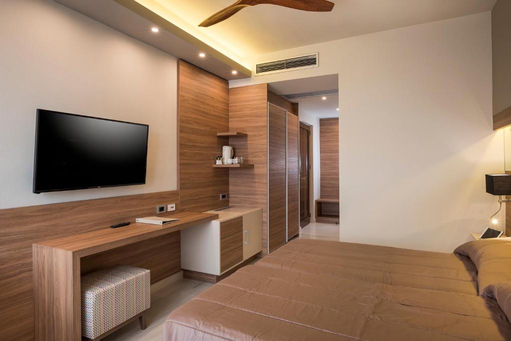a living room with a television and a bed at Atrion Resort Hotel in Agia Marina Nea Kydonias