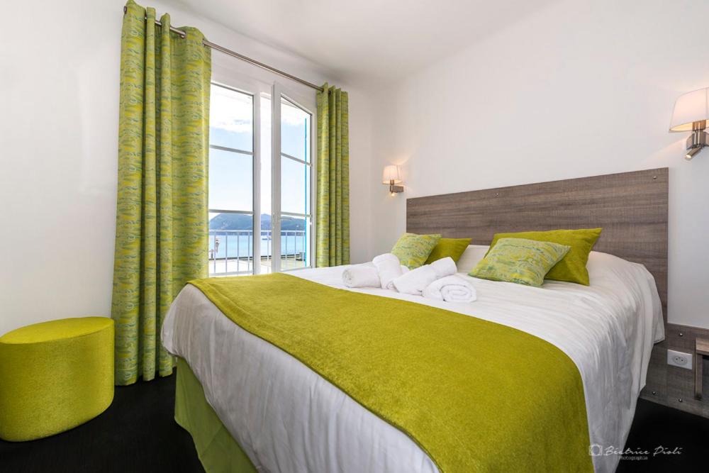 a bedroom with a large bed with a large window at Hôtel George Sand in La Seyne-sur-Mer
