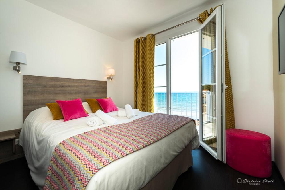 a bedroom with a large bed with a large window at Hôtel George Sand in La Seyne-sur-Mer