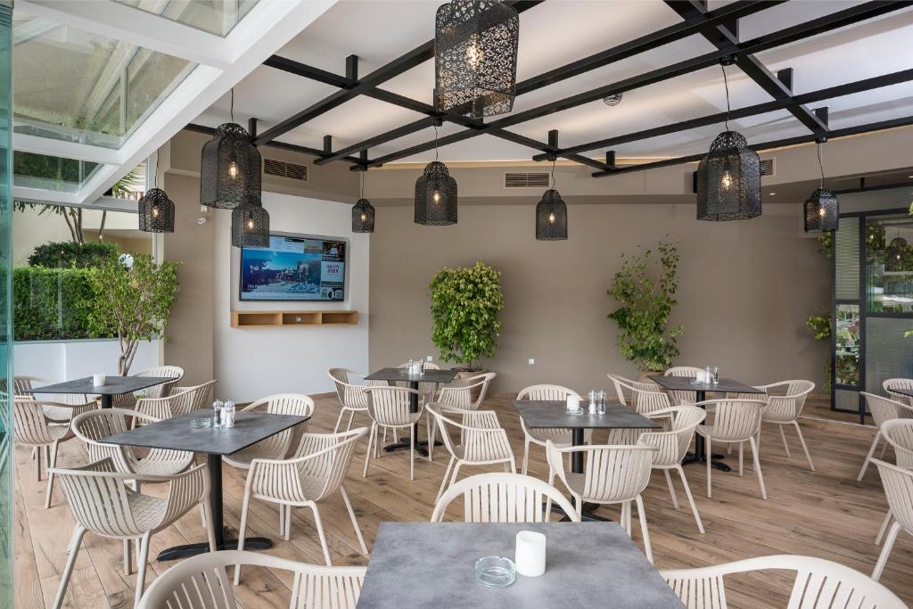 a dining room with tables and chairs and a flat screen tv at Atrion Resort Hotel in Agia Marina Nea Kydonias