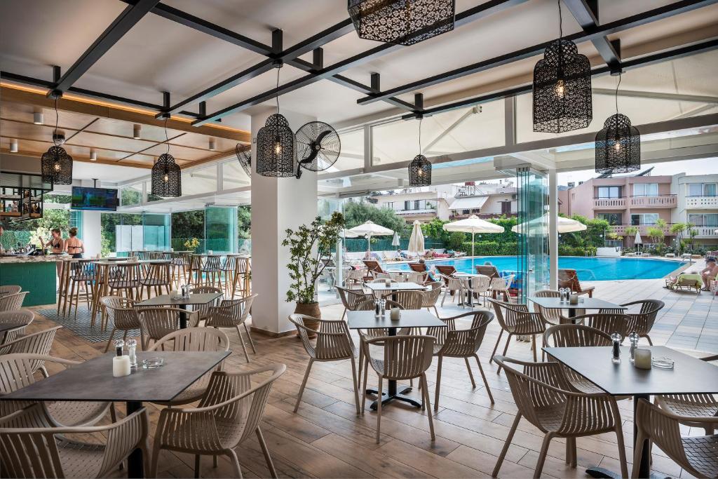 a restaurant with tables and chairs and a pool at Atrion Resort Hotel in Agia Marina Nea Kydonias