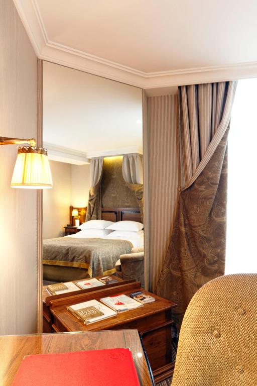 a hotel room with two beds and a table and a mirror at Au Manoir Saint Germain in Paris