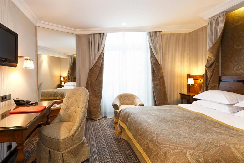 a hotel room with two beds and a desk at Au Manoir Saint Germain in Paris