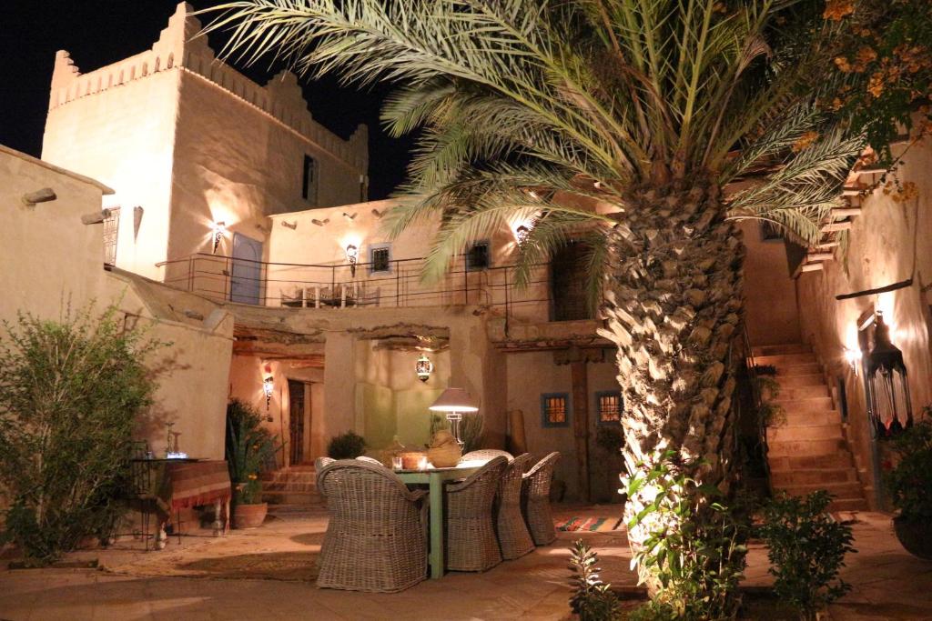 a palm tree in front of a building with a table at Kasbah Gousteau in Taroudant