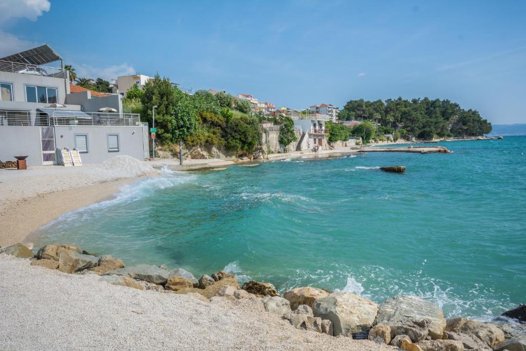 a beach with blue water and buildings and buildings at Breki Apartman in Podstrana