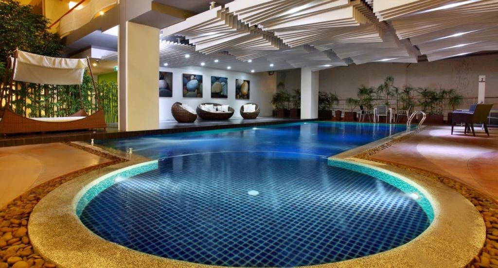 a pool in a hotel lobby with a blue swimming pool at Brighton Hotel in Bangkok