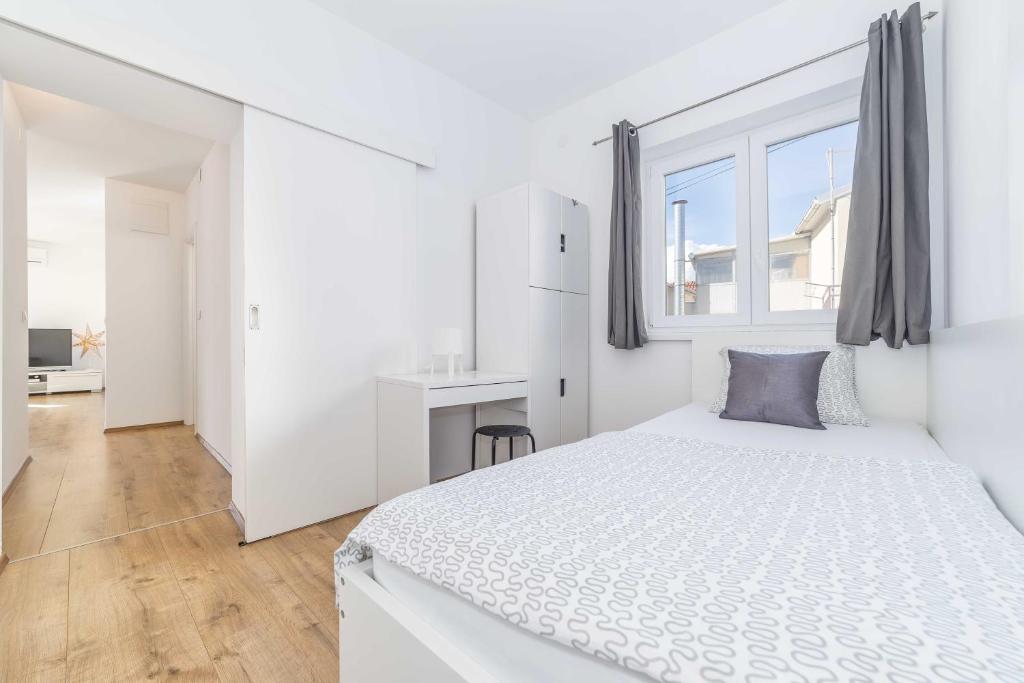 a white bedroom with a large bed and a window at Apartments Tonka Centar in Vodice