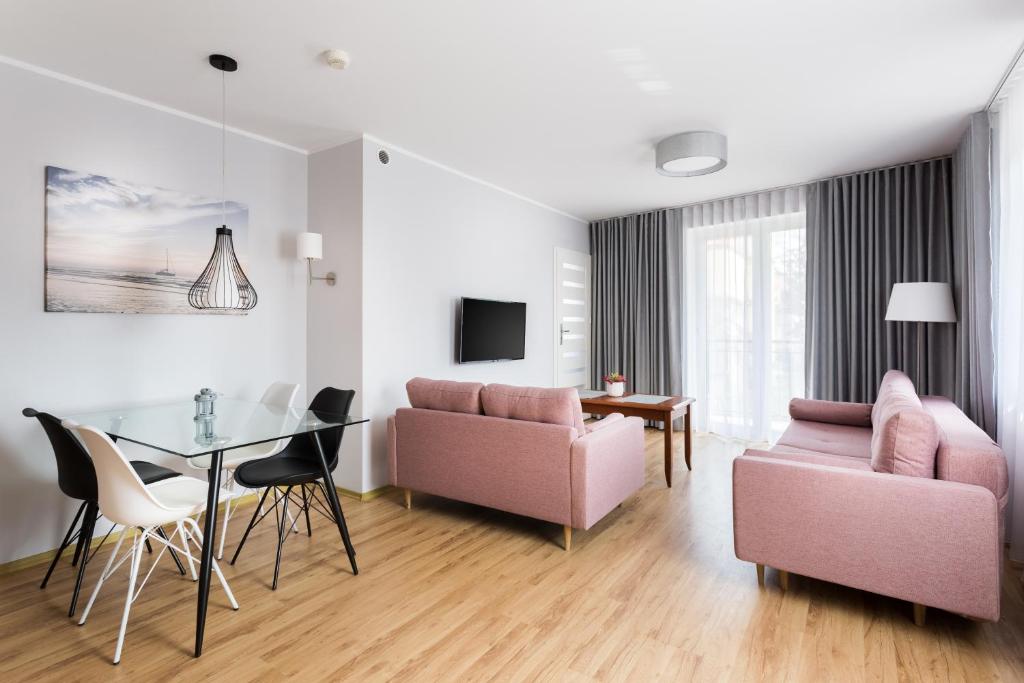 a living room with pink furniture and a table at Elite Apartments Olymp in Kołobrzeg