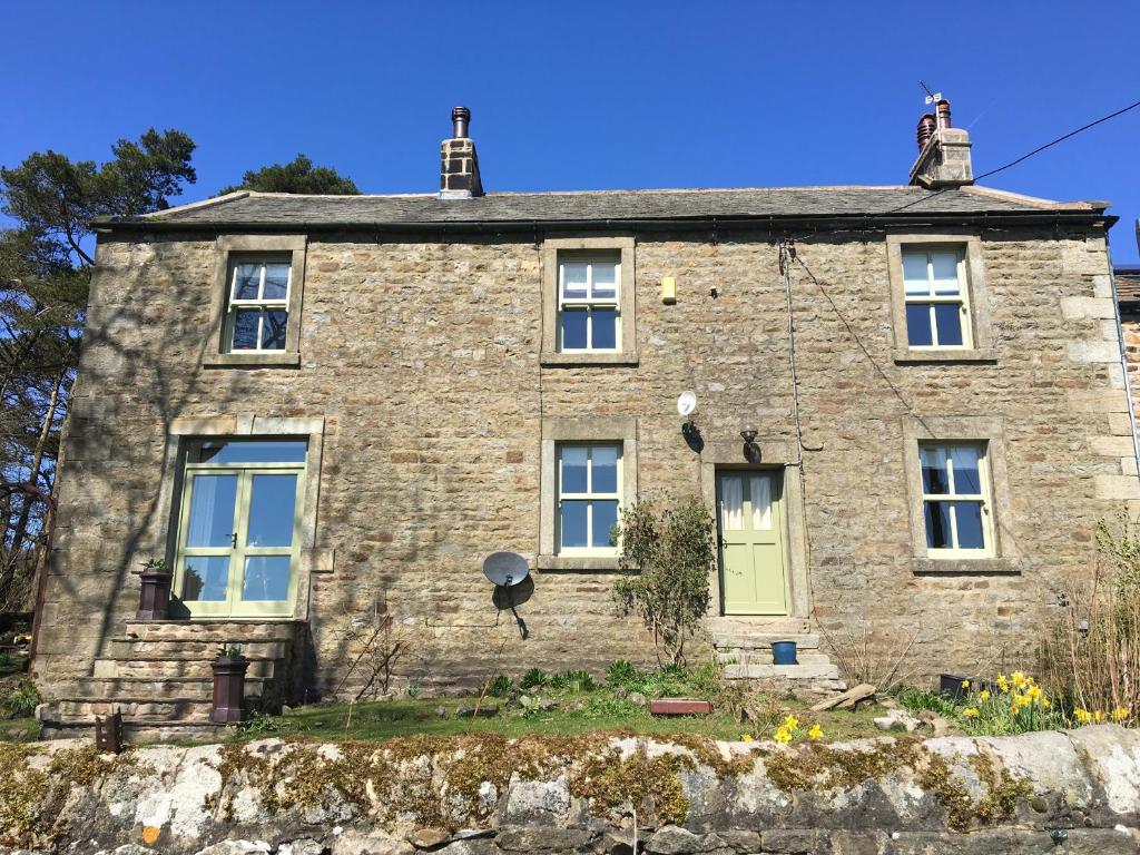 een oud stenen huis met een groene deur bij Dale house barn and B&B in Slaidburn