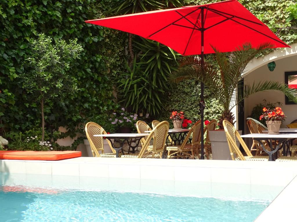 a red umbrella and tables and chairs next to a pool at Chambres d'hôtes Belle Vigneronne in Montagnac