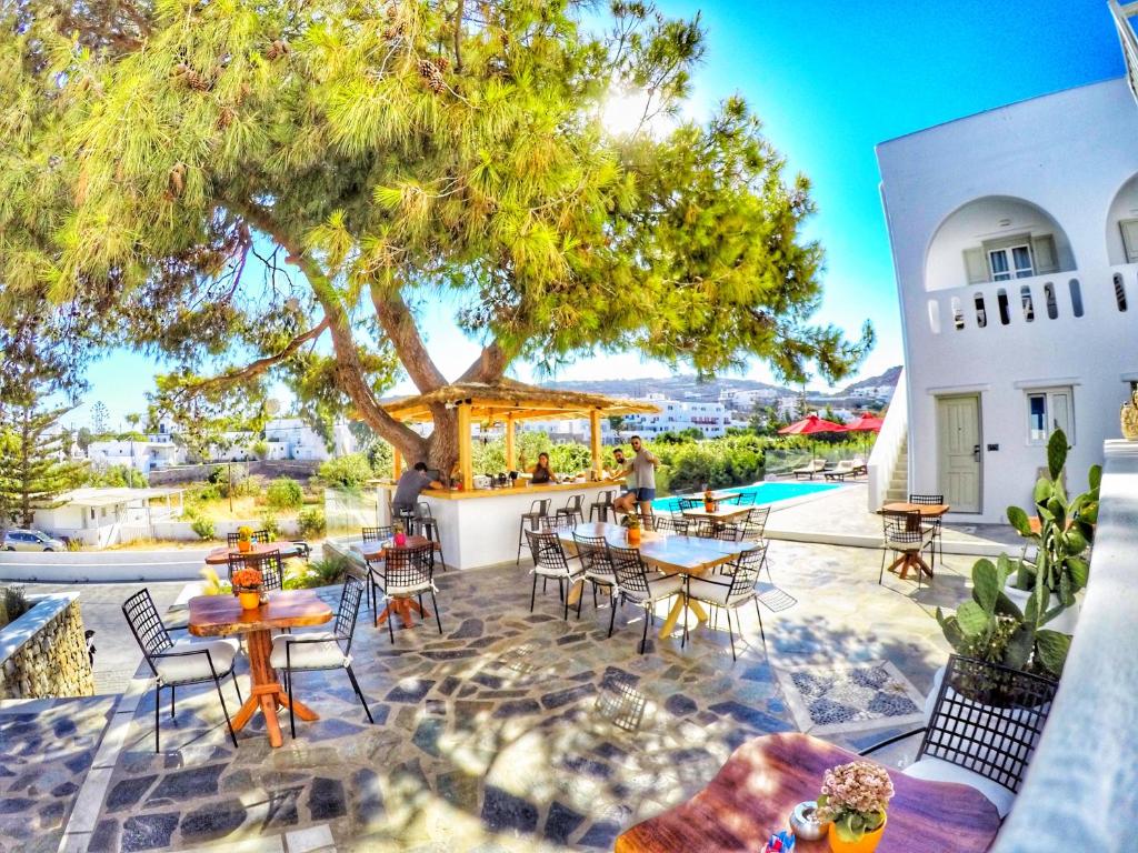 un patio con mesas, sillas y un árbol en Casa Grande Hotel, en Platis Gialos