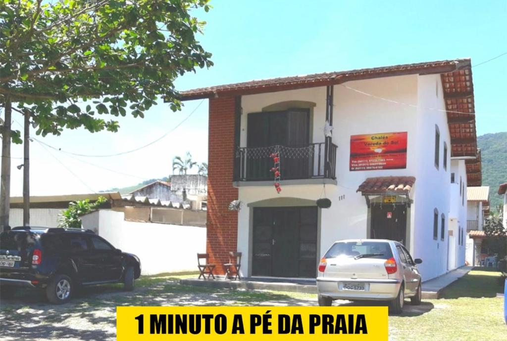 a building with two cars parked in front of it at Pousada Chalés Vereda do Sol in Ubatuba
