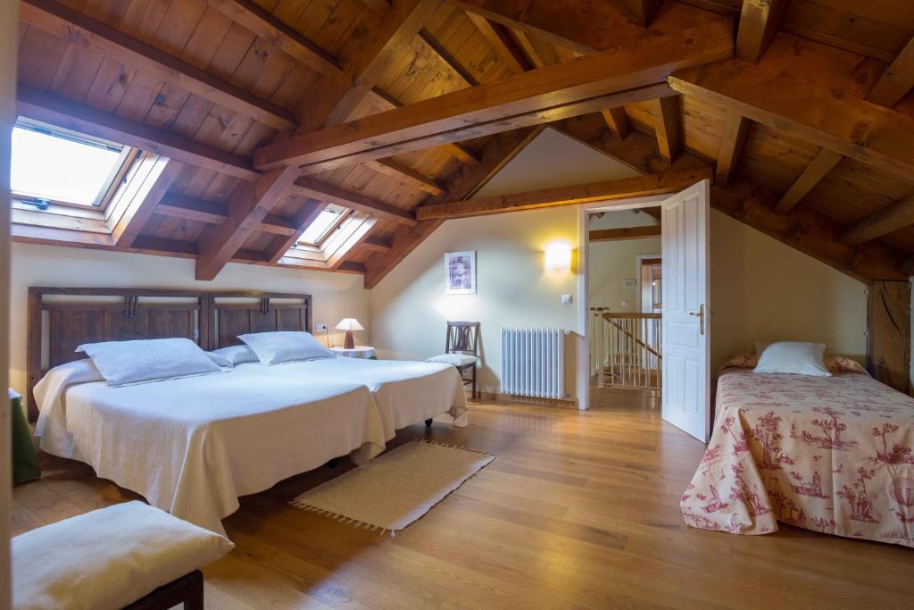 Un dormitorio con dos camas en una habitación con techos de madera. en Casa Rural Graña da Acea, en Monfero